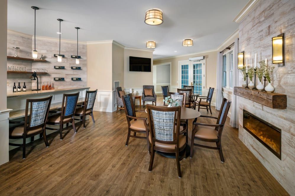 A contemporary dining area featuring wooden flooring, modern lighting fixtures, and a bar section with a television.