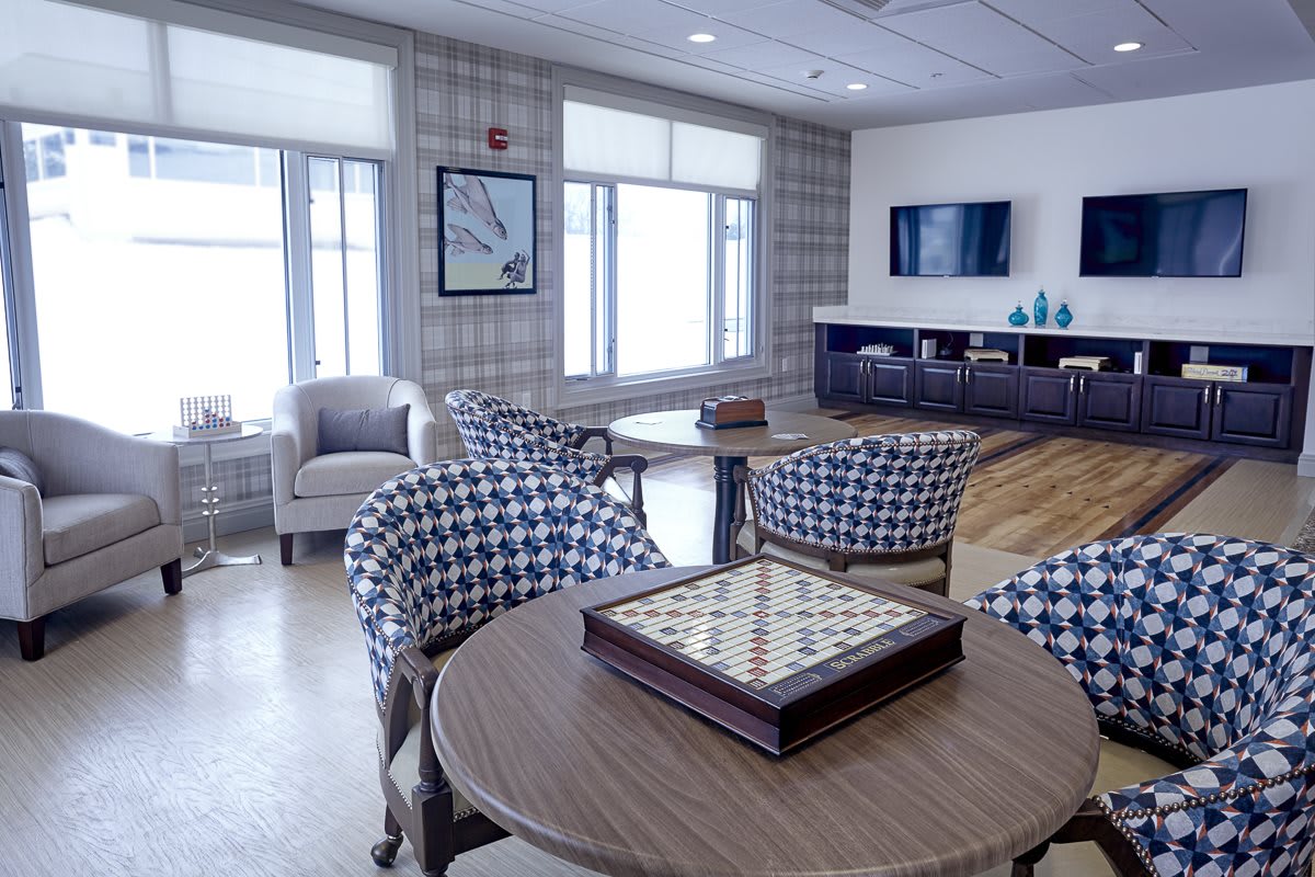 A modern living room with patterned chairs, a board game on the table, and a wall-mounted television.