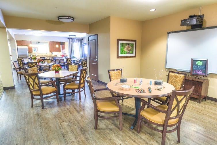 A cozy dining area with wooden tables and chairs, decorated with simple artwork and soft lighting.