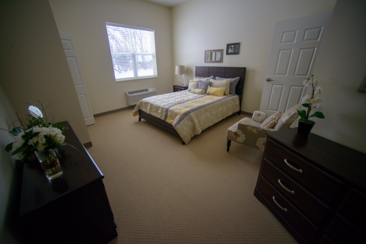 A cozy bedroom with a neatly made bed and warm lighting.