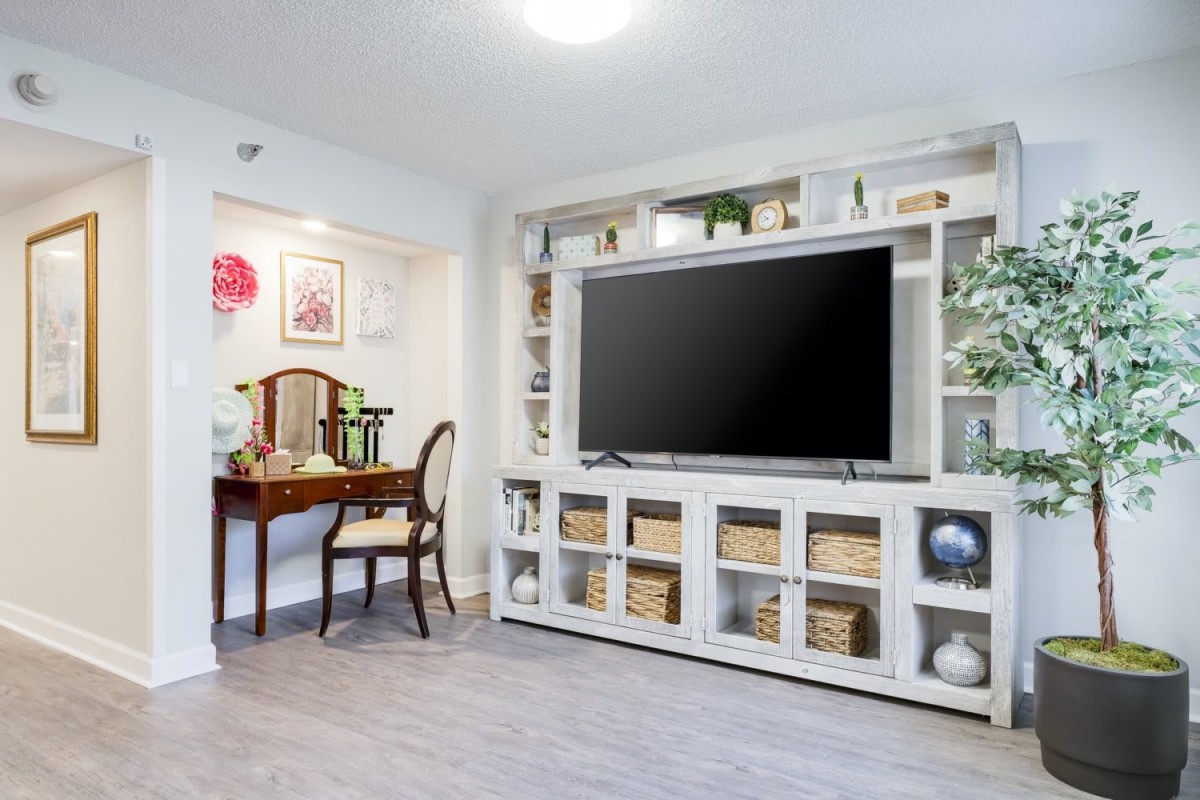 A modern living room with a large television and stylish shelving unit.