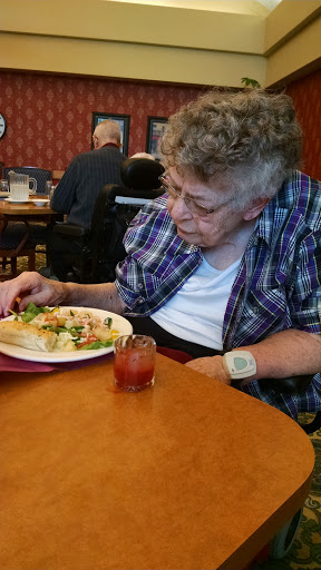 An elderly woman enjoying her meal at a restaurant.