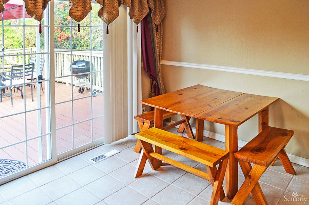 A cozy dining area with a wooden table and benches, next to a sliding glass door leading to the deck.