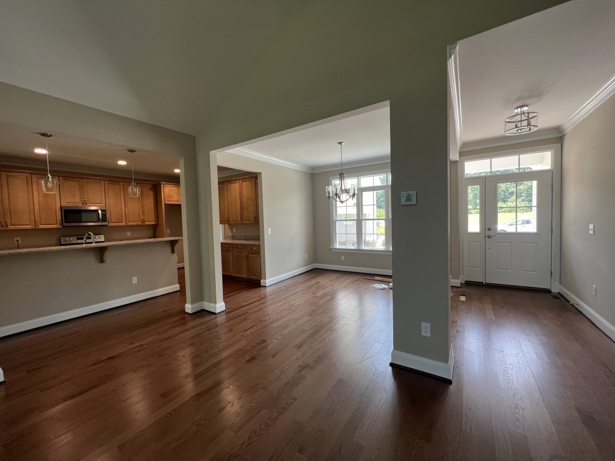 Spacious interior with hardwood floors and natural lighting, featuring an open living area and kitchen.