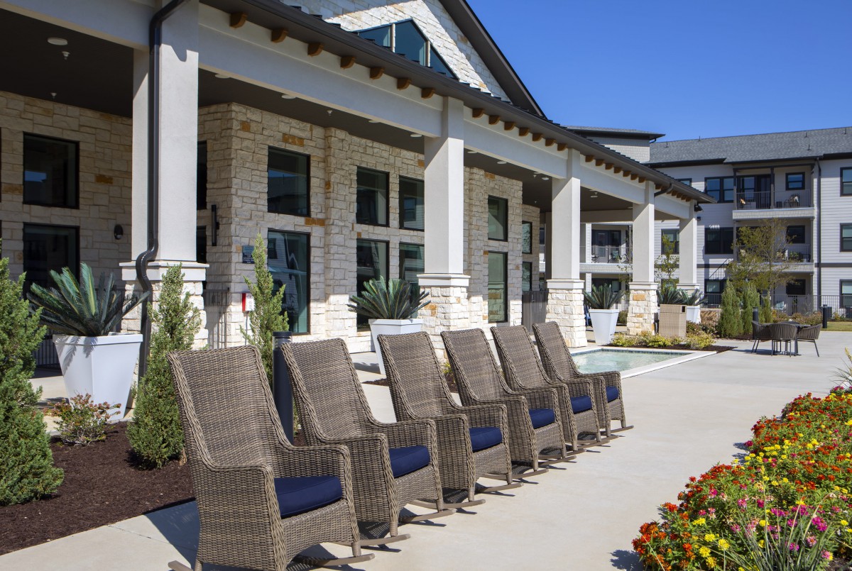 A modern outdoor patio with stylish chairs in front of a contemporary building.
