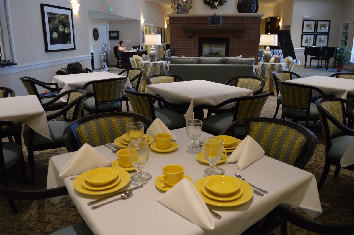 An elegantly set dining area with yellow dishware and comfortable seating.