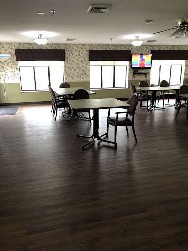 A spacious dining area featuring tables and chairs, illuminated by natural light from large windows.