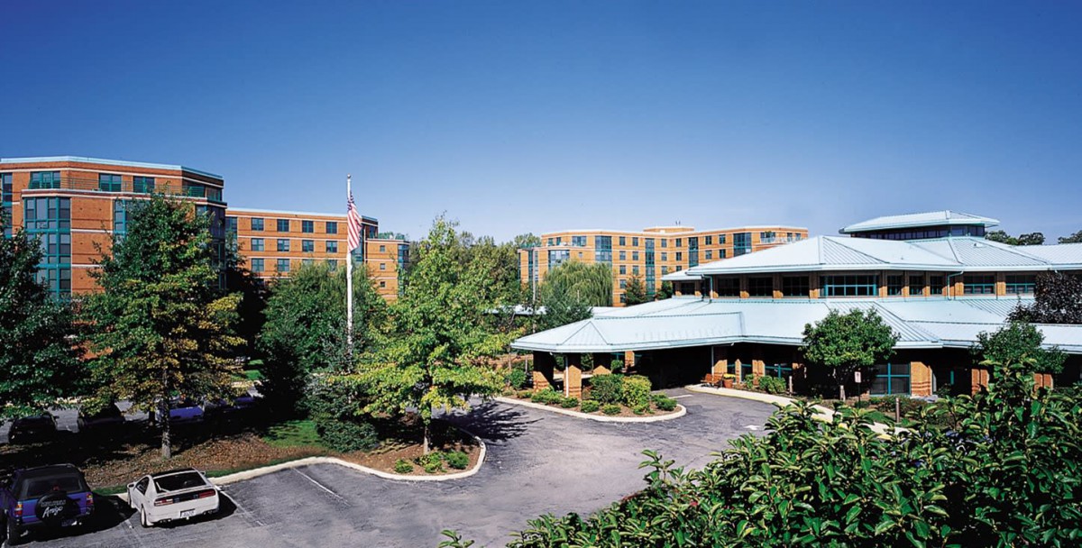 A hotel building surrounded by landscaped gardens and a driveway.