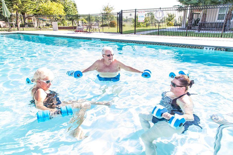 A group of seniors engaging in aqua aerobics in an outdoor pool.