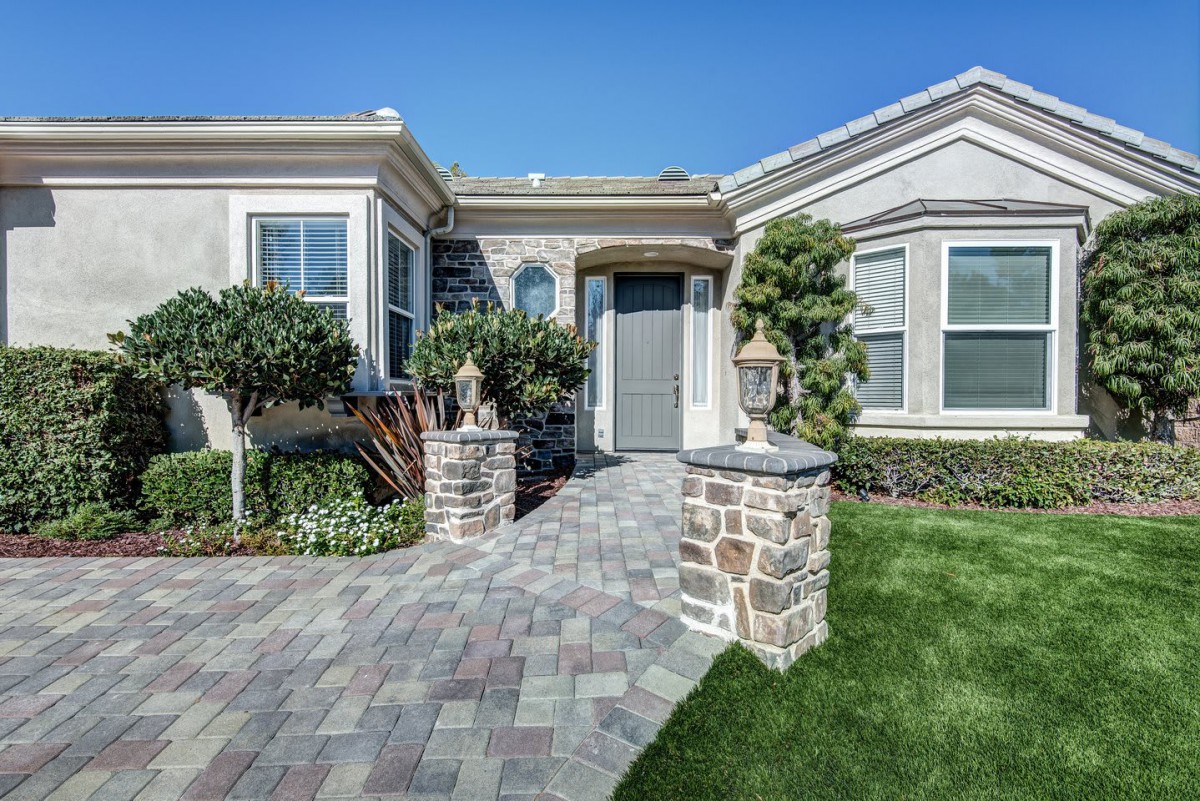 A well-maintained residential house with a paved pathway and manicured landscaping.