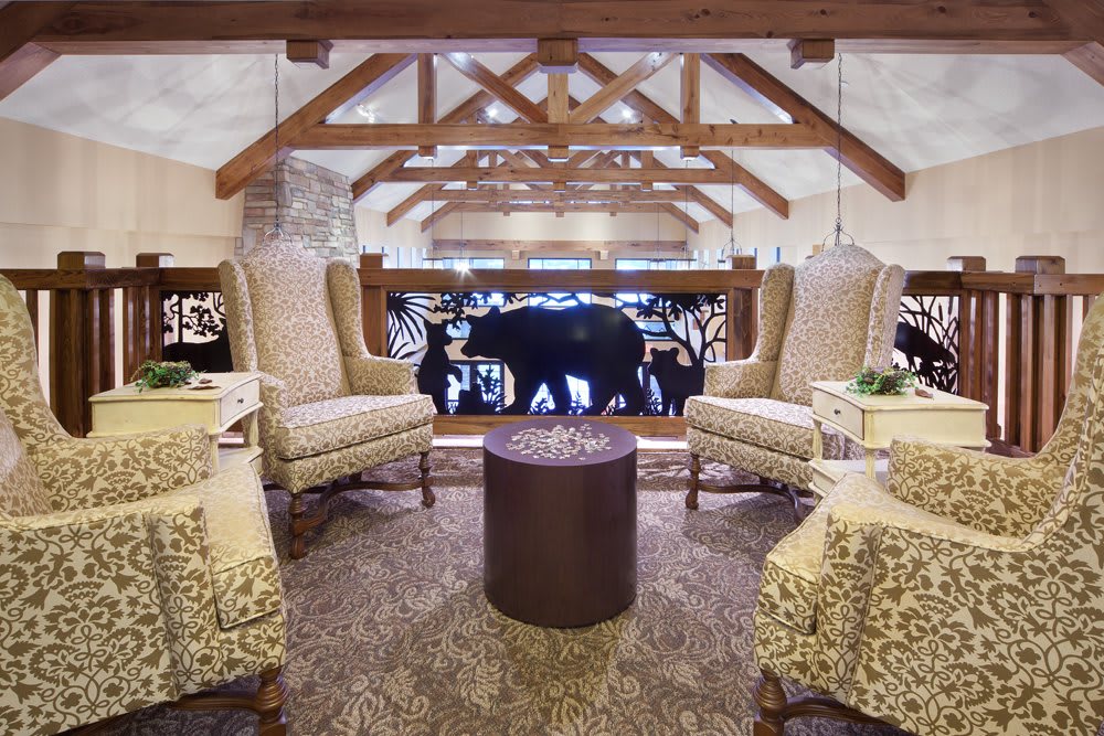 A cozy lounge area featuring armchairs, a round table, and rustic wooden beams.