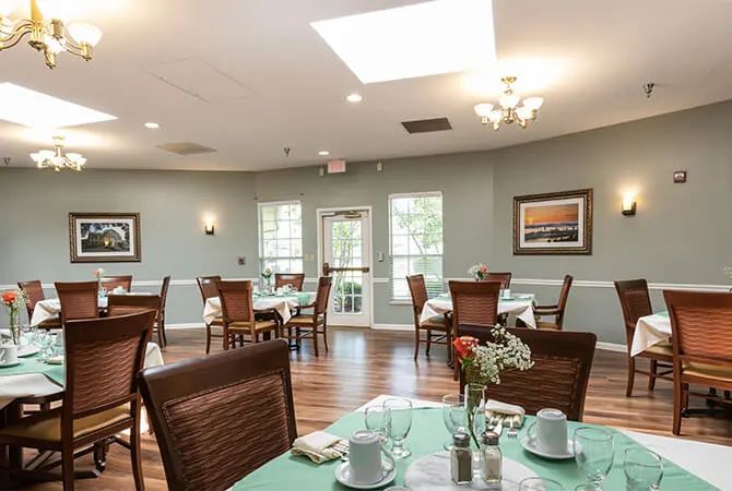 A spacious and elegantly decorated dining room with neatly arranged tables and chairs, filled with natural light from large windows.