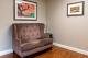 A cozy living room with a tufted sofa and framed artwork on the walls.