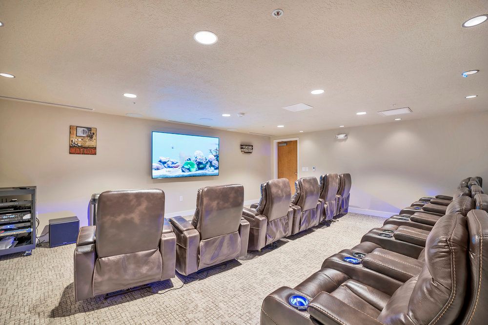 A cozy home theater with multiple recliner chairs and a large projector screen.