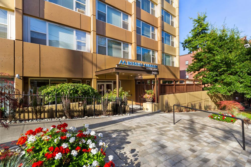 Entrance to a hotel with surrounding greenery and flowers.