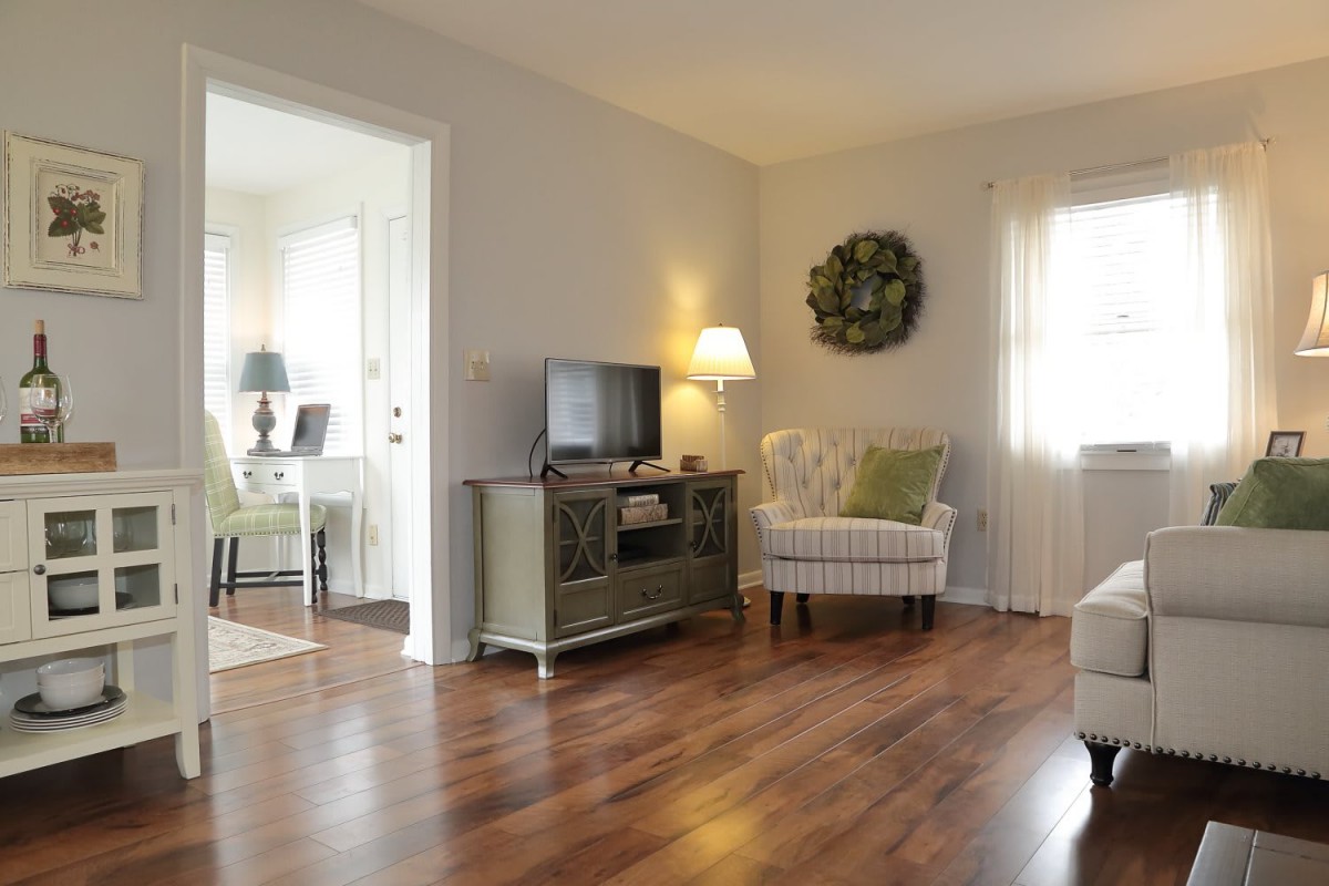 A cozy living room featuring hardwood floors, a comfortable chair, and a television.