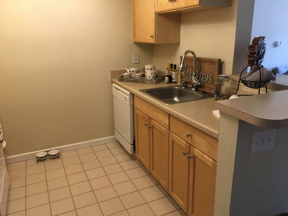 A small kitchen with wooden cabinets, a sink, and a dishwasher.