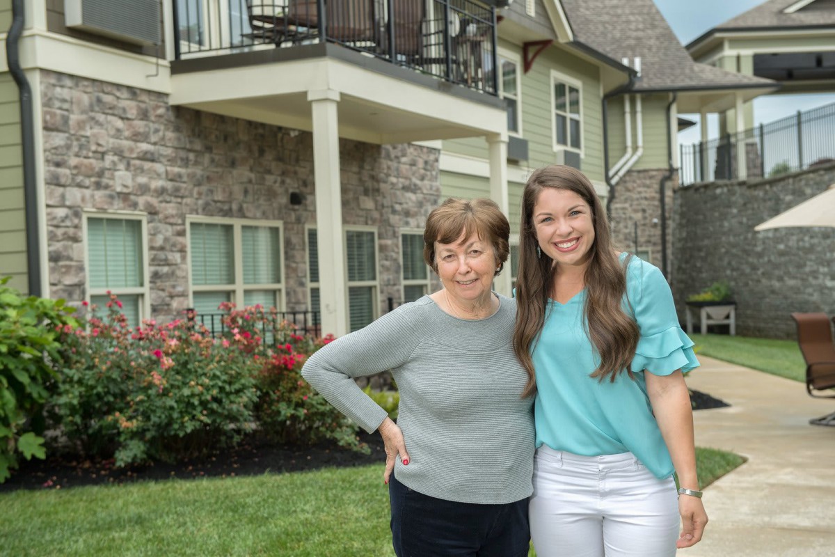 Two people standing together outside a house.