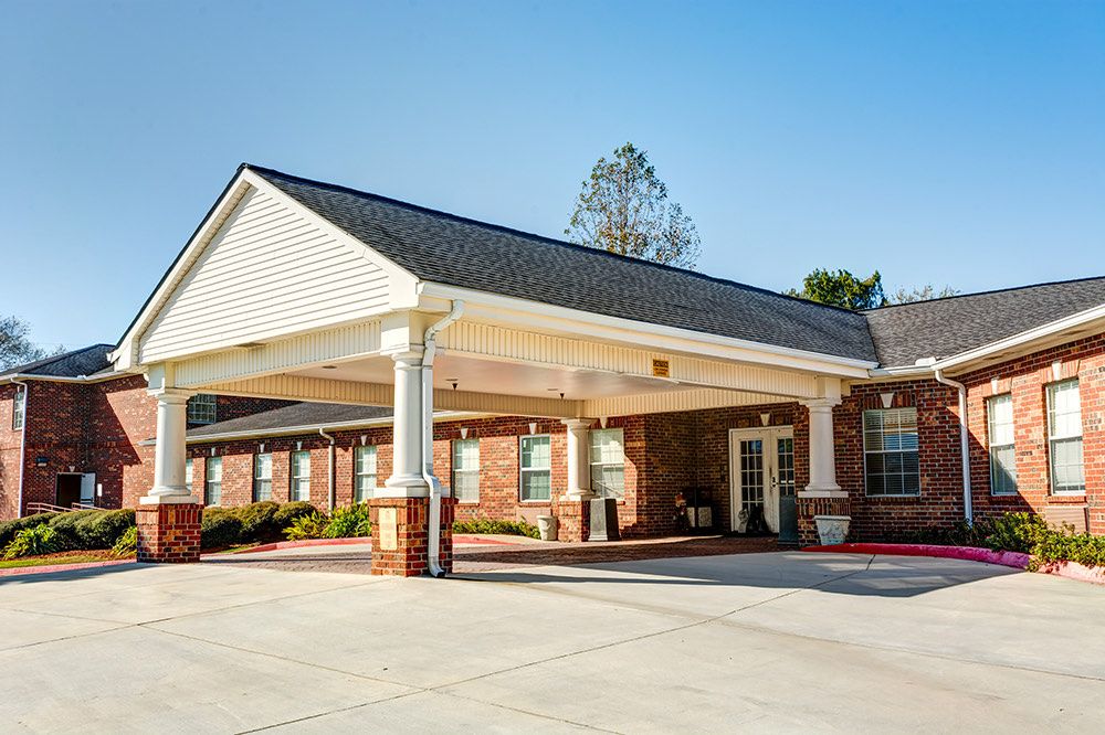 A building with a covered entrance and parking area on a clear day.