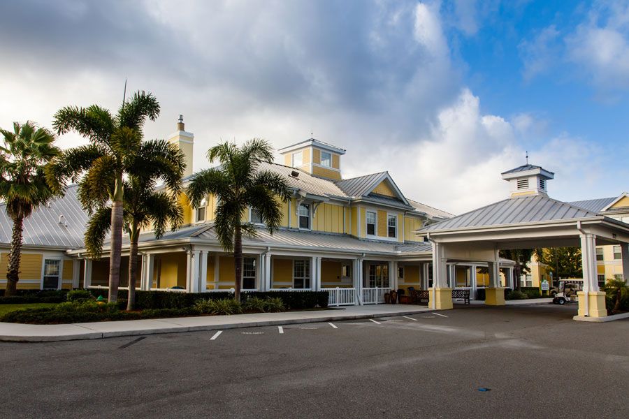 A large yellow building with palm trees and a cloudy sky.