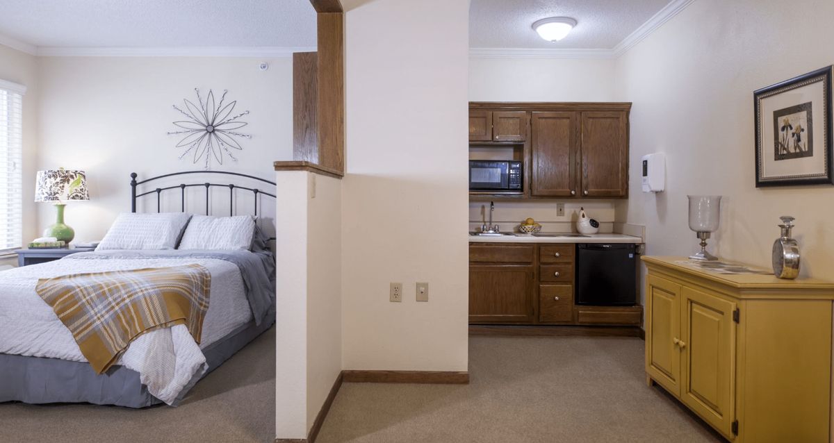 A cozy studio apartment with an open layout featuring a small kitchen and adjacent bedroom area.