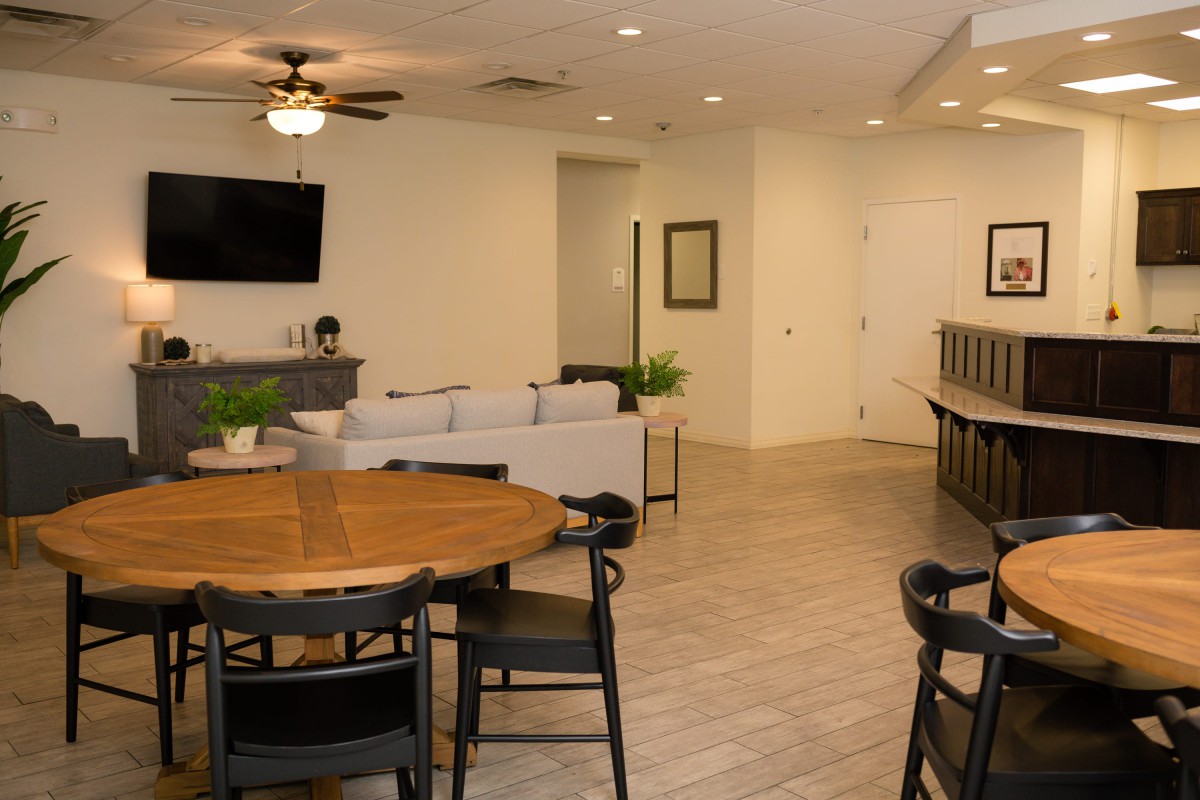A modern living and dining area featuring comfortable seating, a television, and a ceiling fan in an open-plan layout.