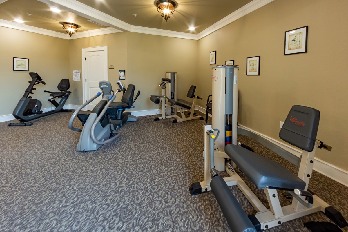 A small gym with various exercise machines, including stationary bikes and weight stations.