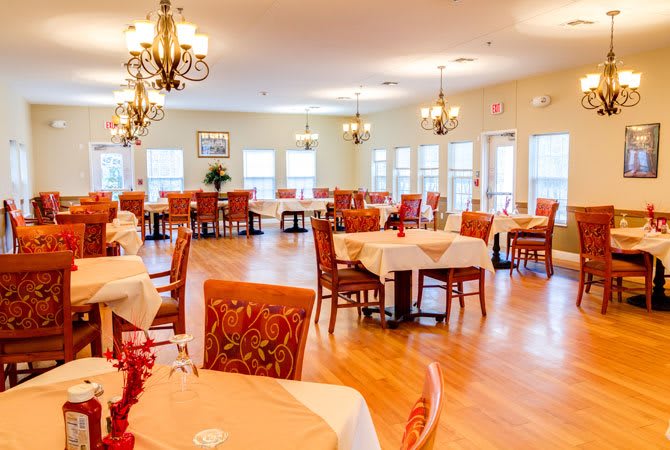 An elegant dining room with arranged tables and chairs, adorned by chandeliers.