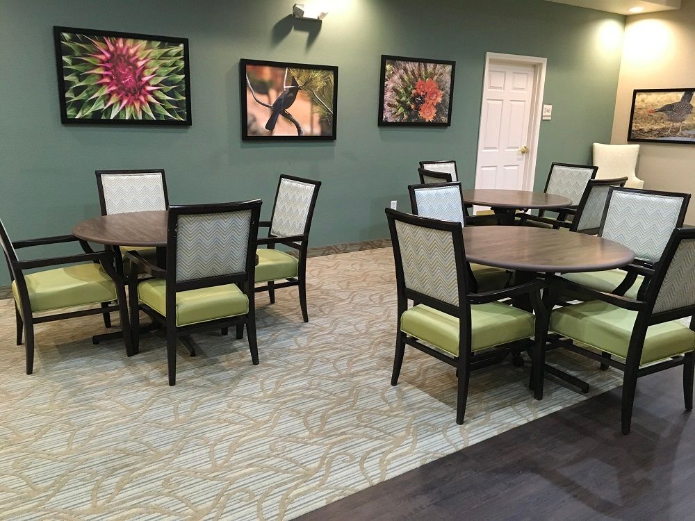 A cozy dining area with neatly arranged tables and chairs, decorated with colorful artwork on the walls.