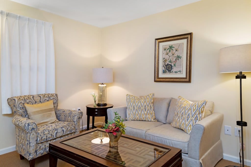 A cozy living room with a sofa, armchair, coffee table, and soft lighting.