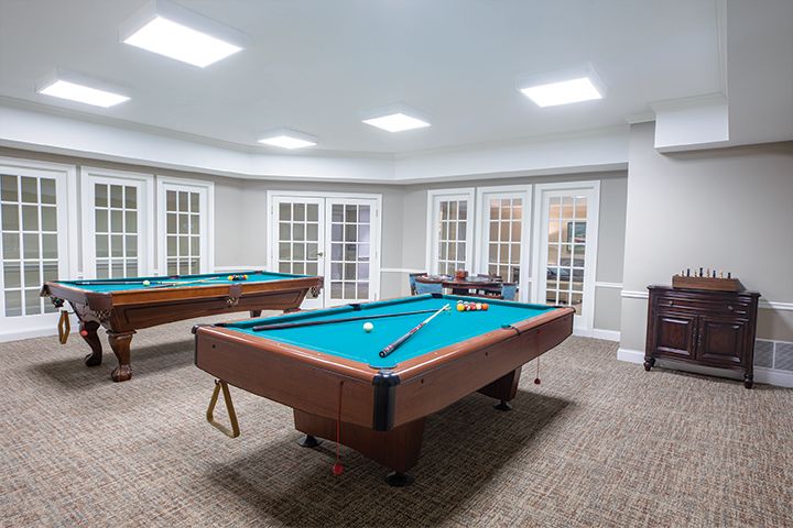 A spacious game room with two pool tables and bright lighting.