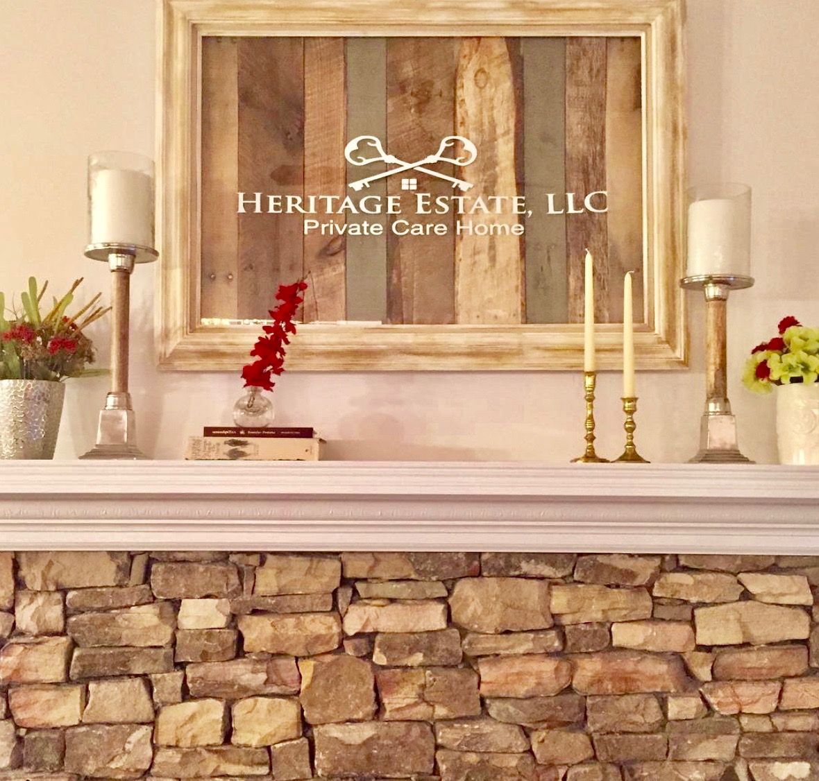 A rustic mantel decorated with candles, stone accents, and a framed sign.