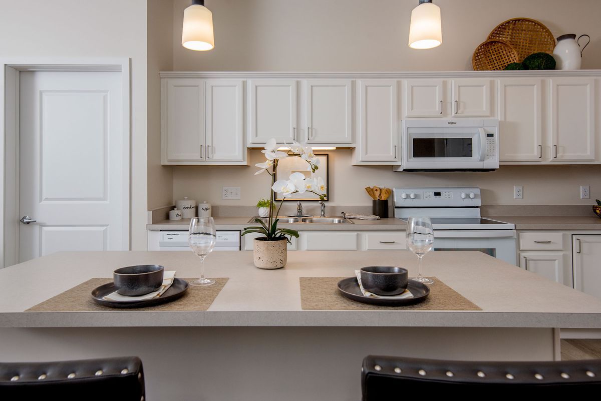 A modern kitchen with white cabinets and a dining setup on the bar counter.