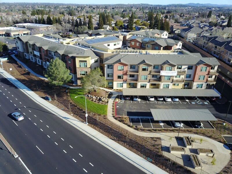 Aerial view of a residential apartment complex with adjacent roads and parking areas.