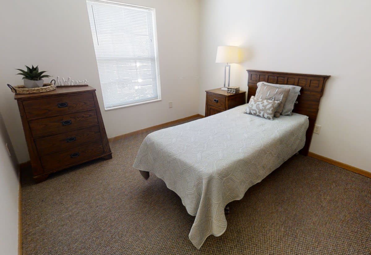 A minimalist bedroom with a single bed, wooden furniture, and soft lighting.