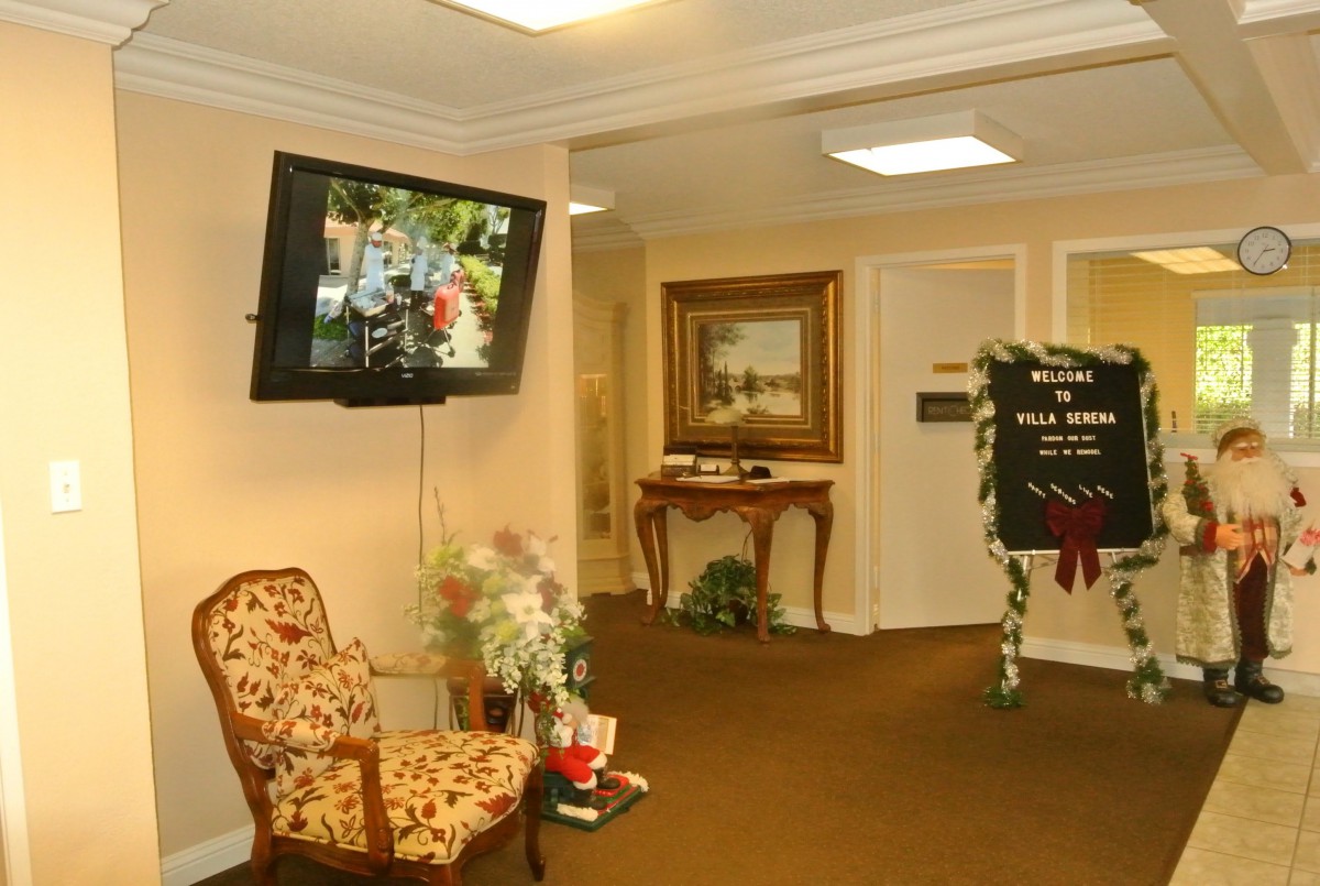 A cozy lobby area with a floral chair, television, and elegant decor.