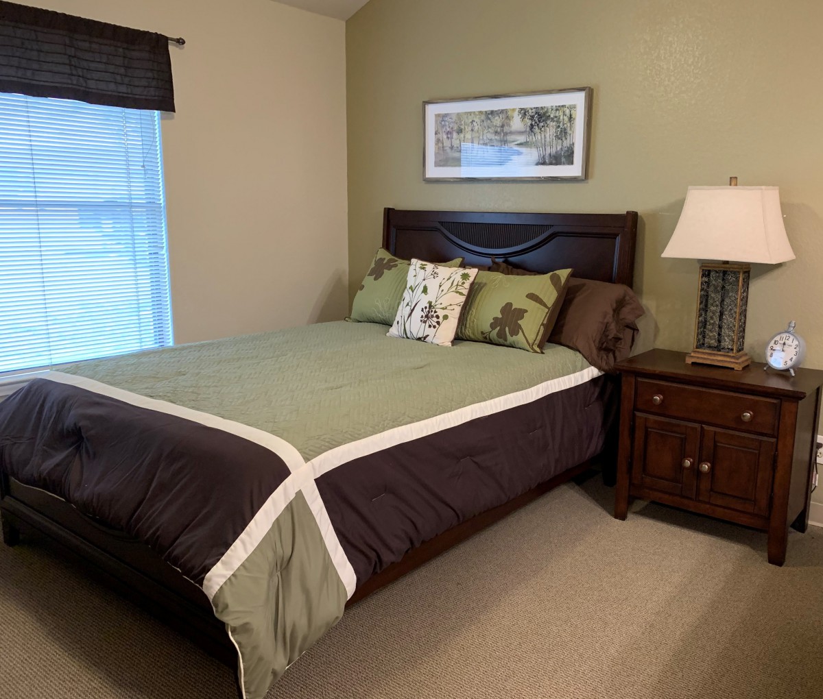 A cozy bedroom with a neatly made bed, nightstand, and lamp.