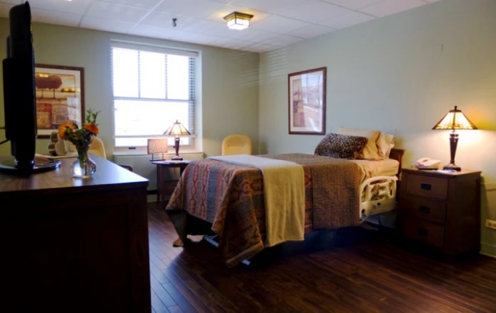 A cozy bedroom with a hospital bed, featuring a large window and warm lighting.