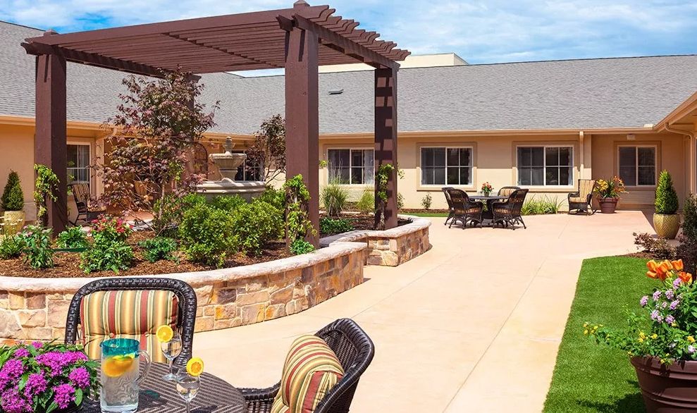 A sunny patio area with comfortable outdoor seating, a garden, and a pergola for shade.
