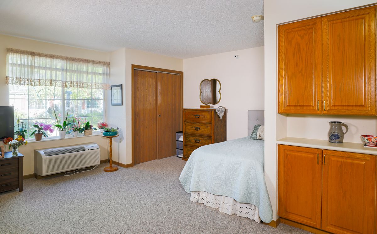 A cozy bedroom with a single bed, dresser, and window.