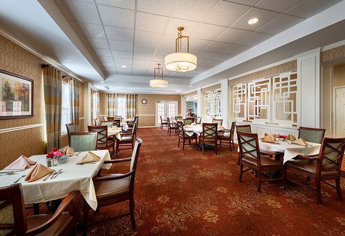 An elegant dining room with neatly arranged tables and chairs, featuring chandeliers and tasteful decor.