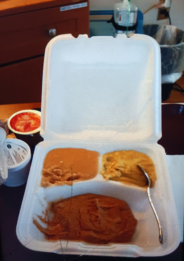 A takeout meal featuring two different types of sauce in a styrofoam container.
