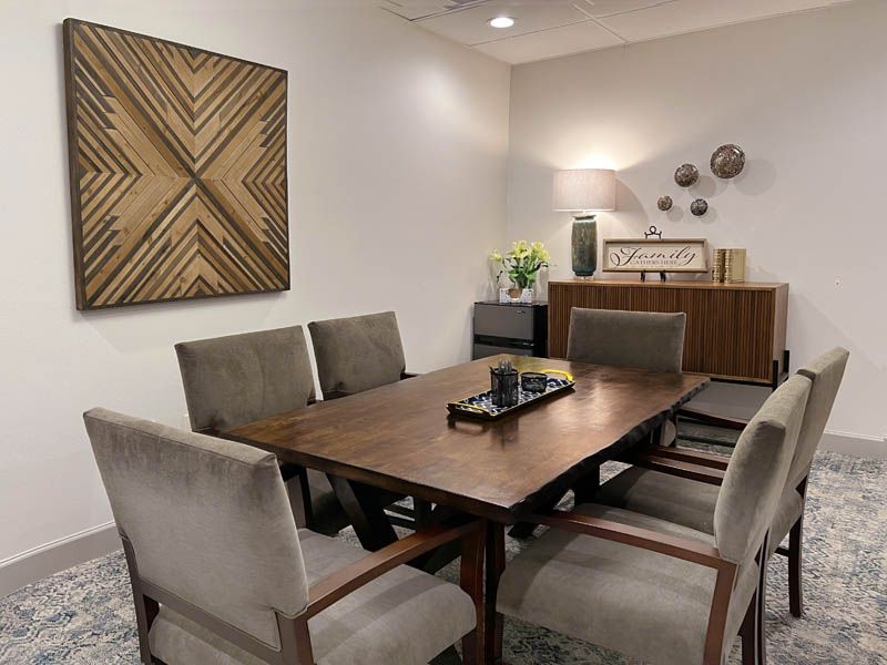 A modern dining room featuring a wooden table, upholstered chairs, and wall art.