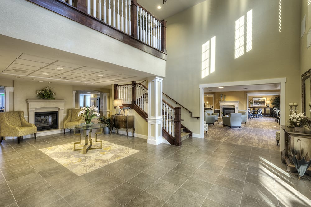 A spacious and modern living area with an open floor plan, featuring a prominent staircase and abundant natural light.