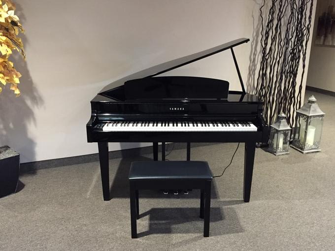 A sleek black grand piano with a matching bench in a modern room.