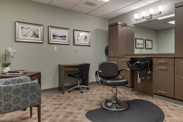 A well-organized salon interior with a barber chair, mirrors, and framed artwork on the walls.