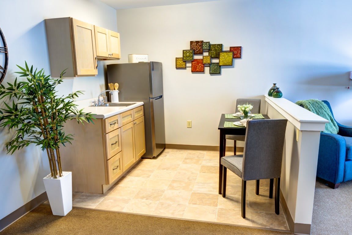 A cozy apartment kitchen with a small dining area and colorful wall art.