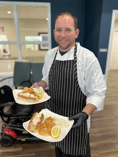 A chef proudly presents two beautifully plated meals.