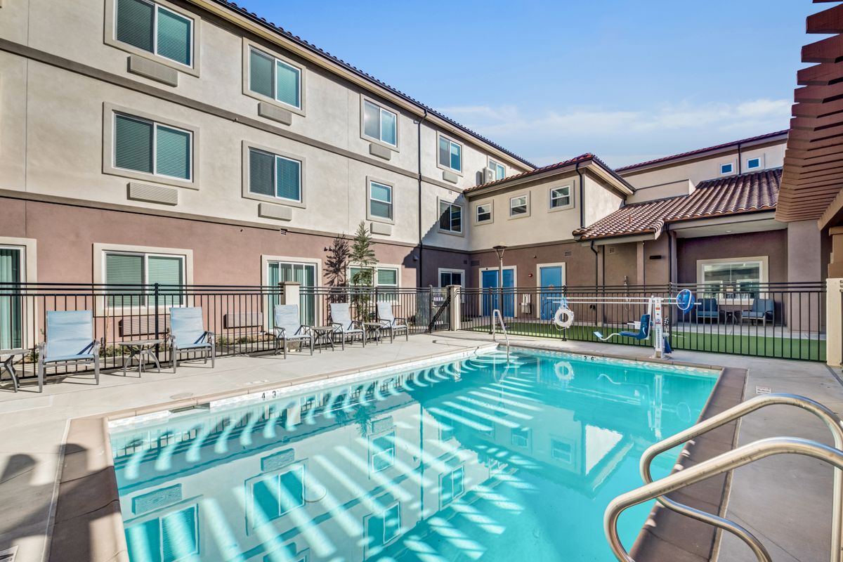 An outdoor swimming pool next to a hotel building on a sunny day.