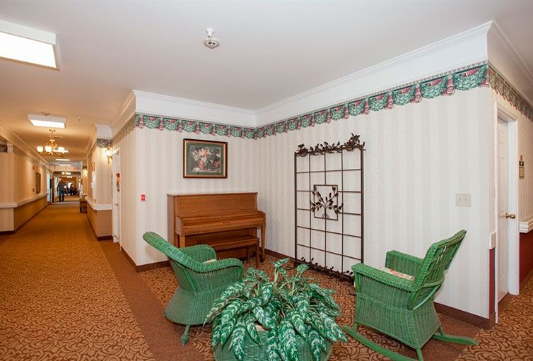 A cozy hallway with a piano, wicker chairs, and decorative elements.